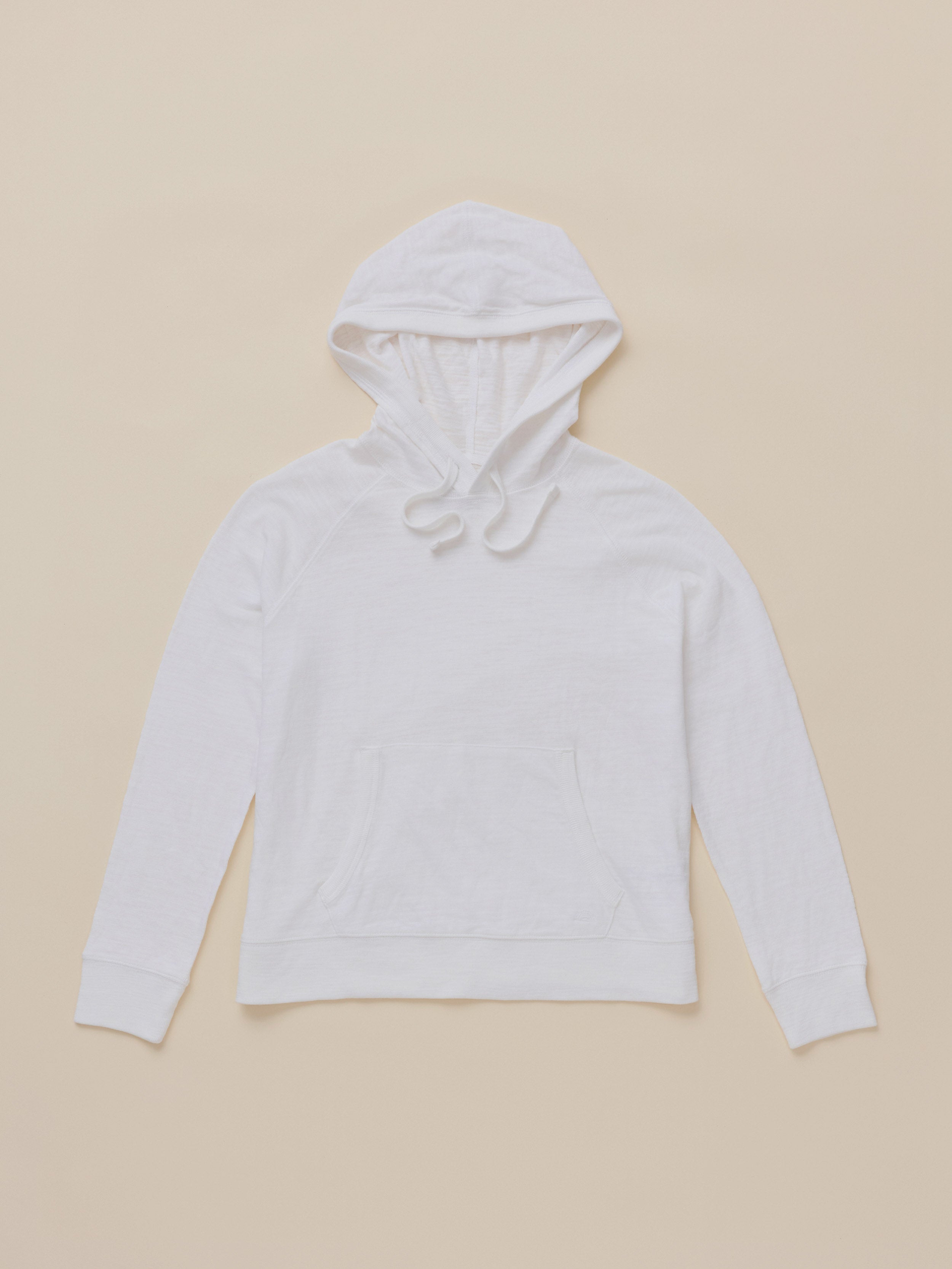 A plain white hoodie with a drawstring hood and front kangaroo pocket, laid flat against a solid beige background.
