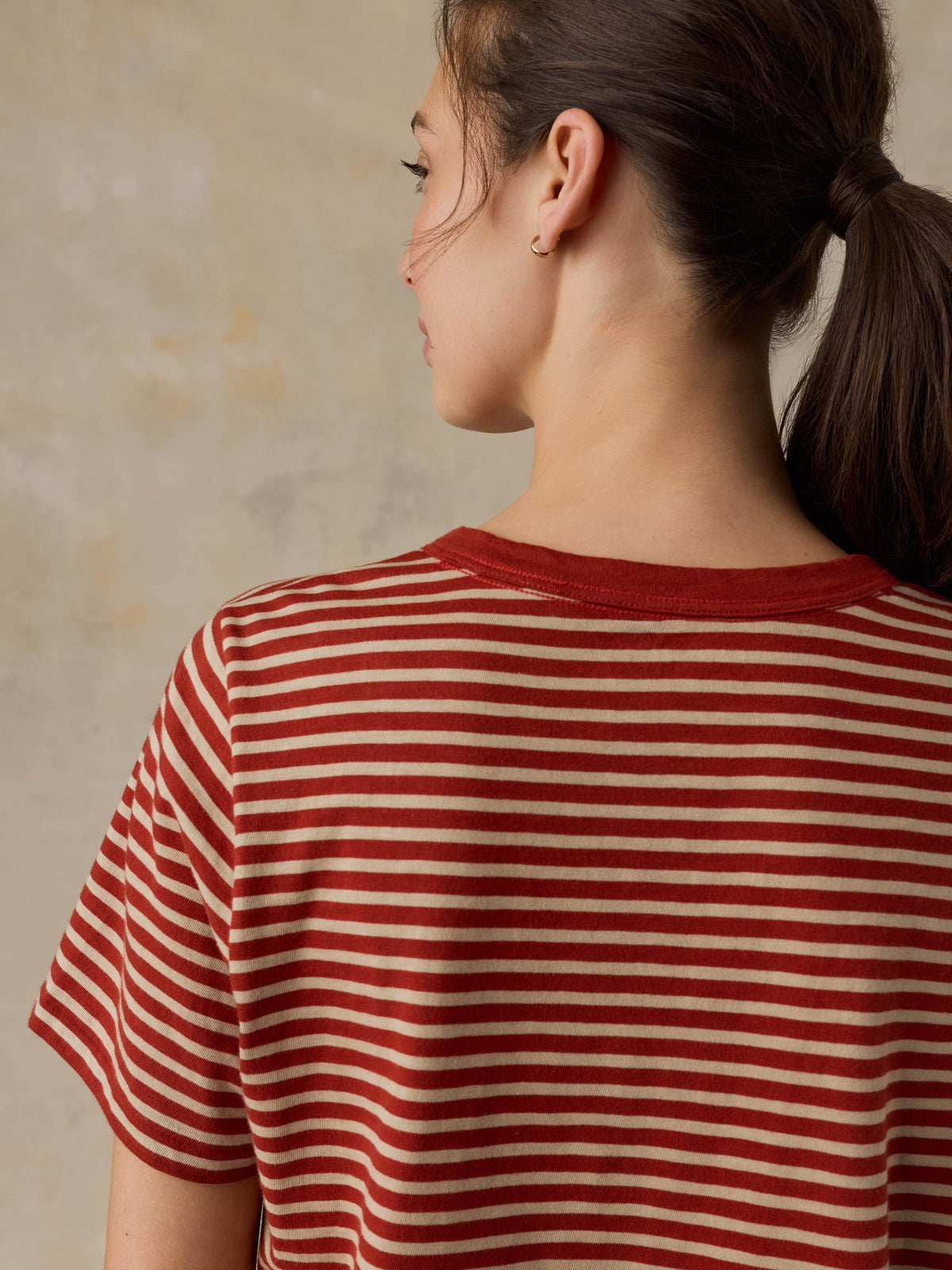 Woman wearing a red striped shirt against a beige background, image 7 of 8