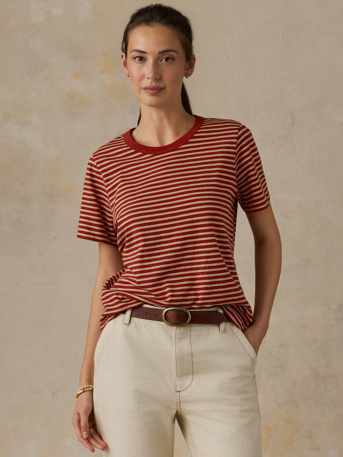 Woman wearing a red striped shirt and beige pants against a beige background, image 4 of 8
