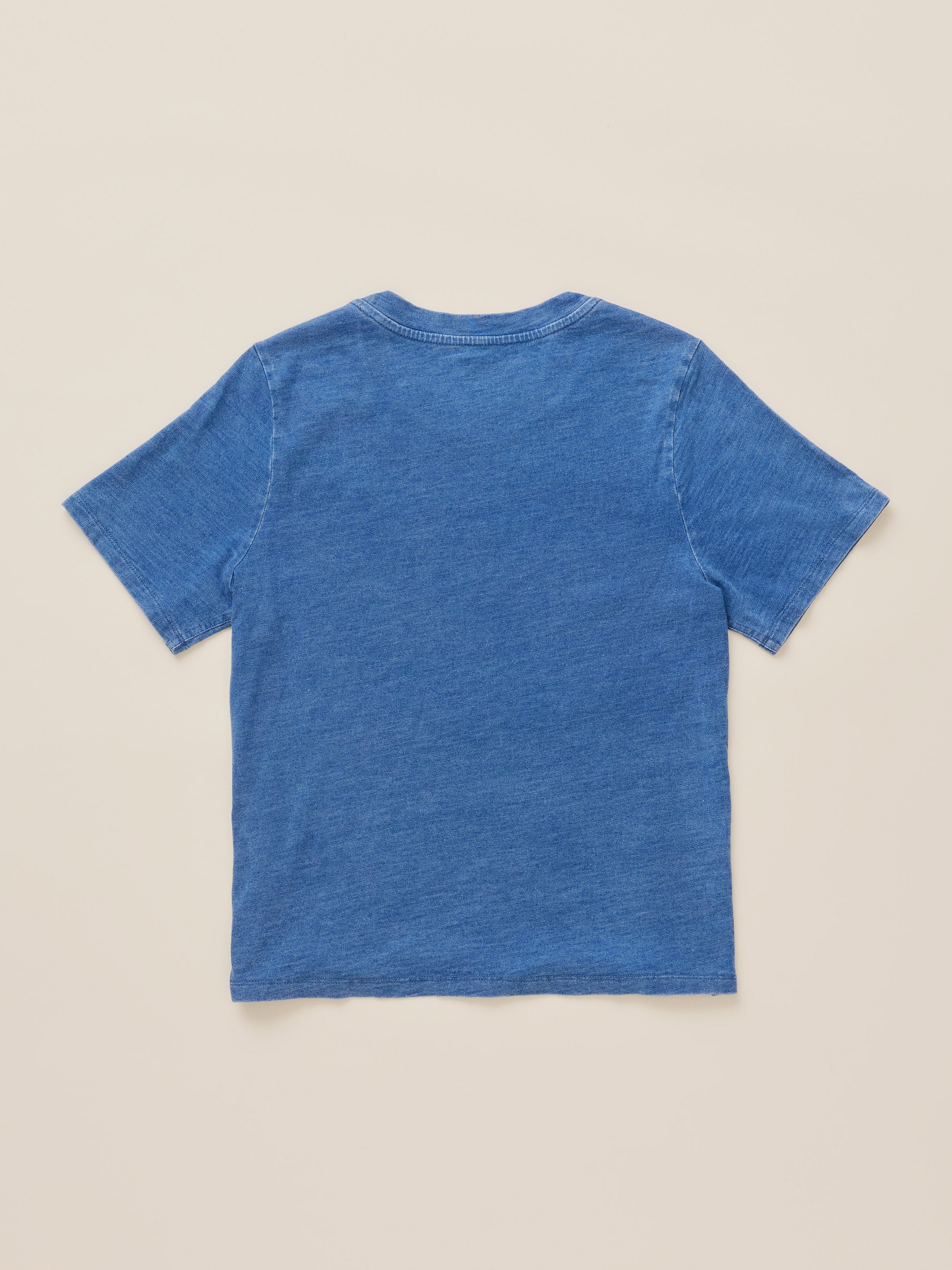 A blue short-sleeve crewneck t-shirt shown from the back, laid flat on a light beige background.