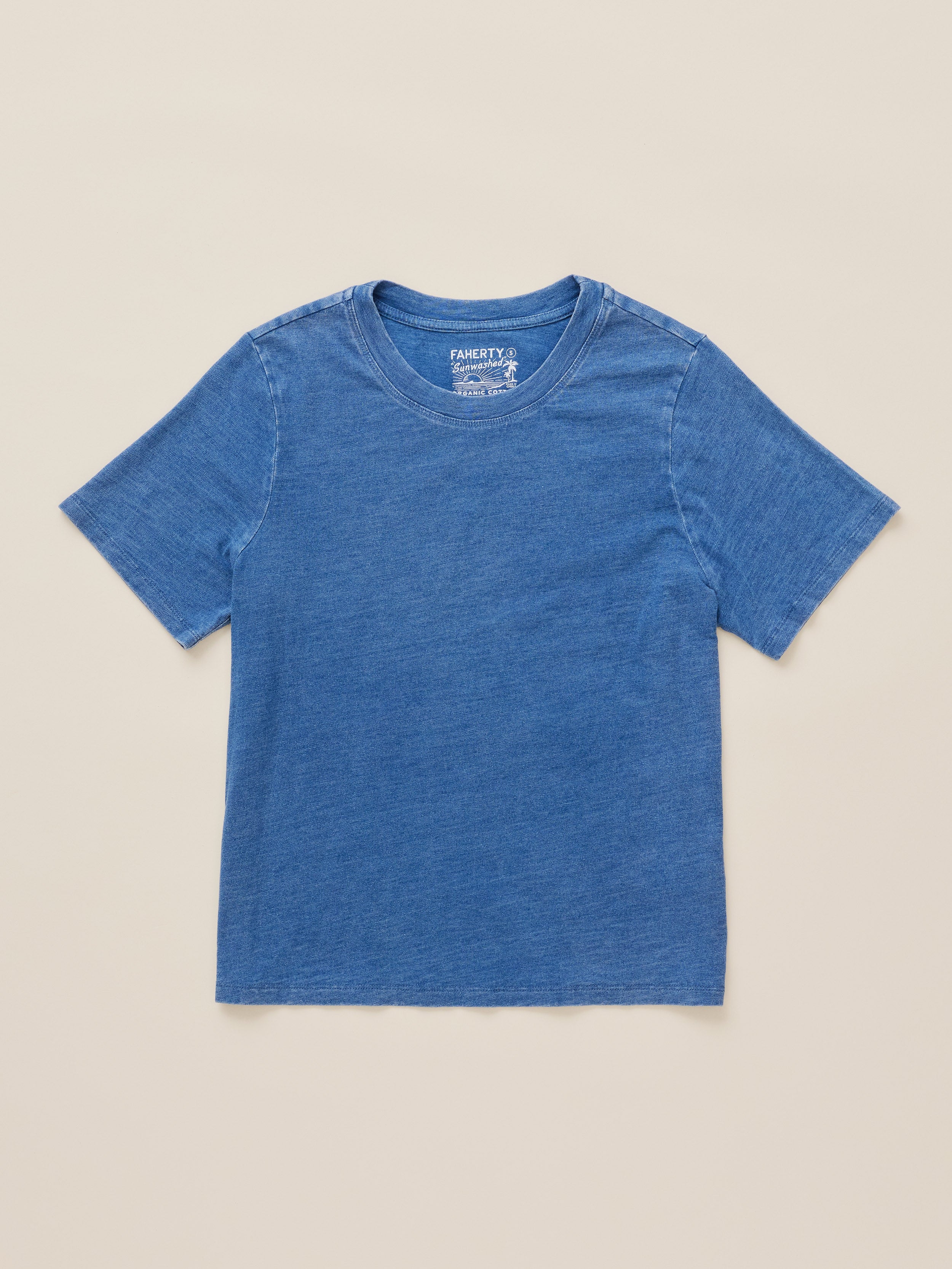 A short-sleeve crewneck t-shirt in a heathered medium blue color, laid flat against a solid light beige background. The brand name Faherty is visible on the inner neck label.