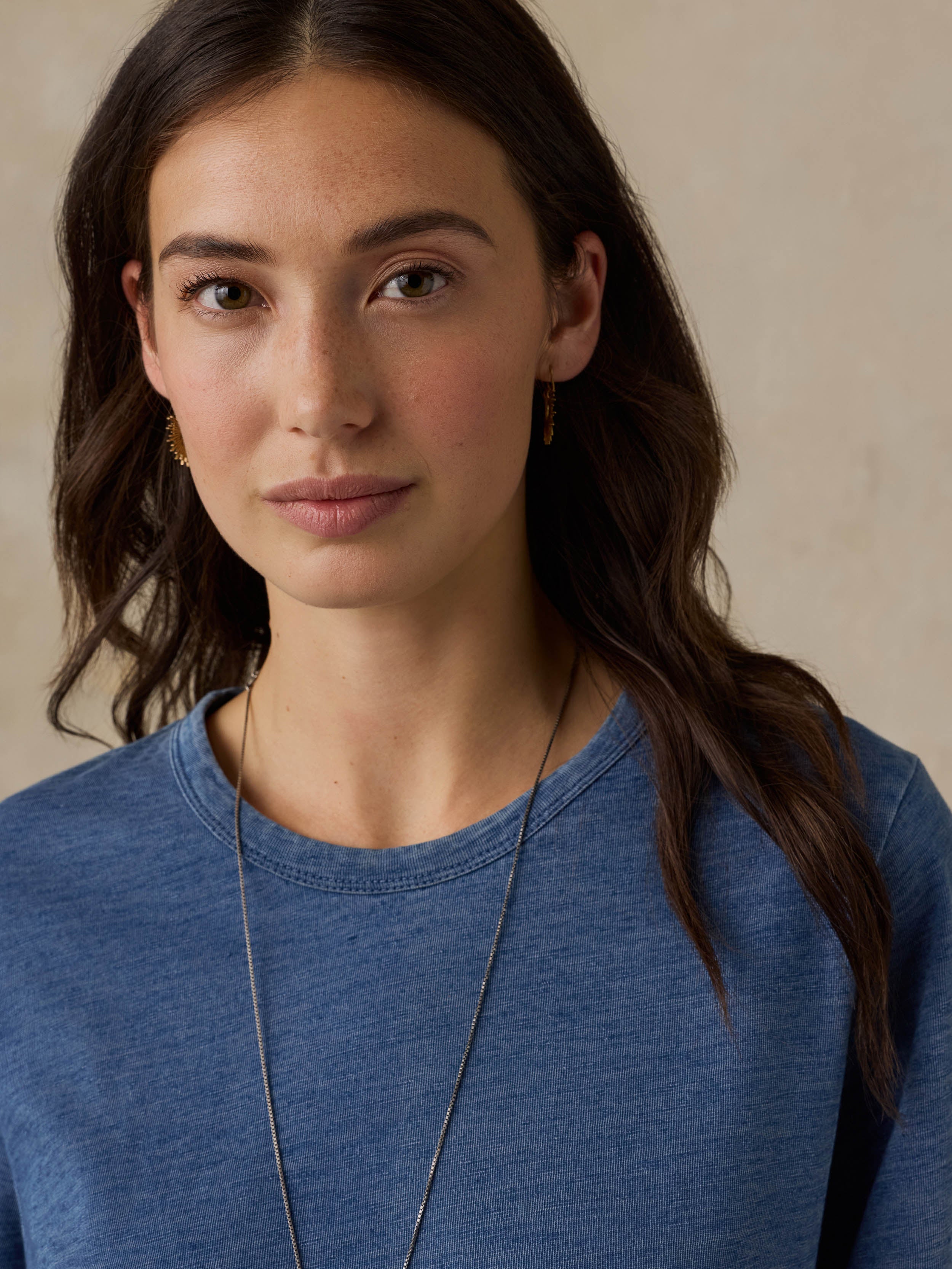 Woman wearing a blue t-shirt against a beige background