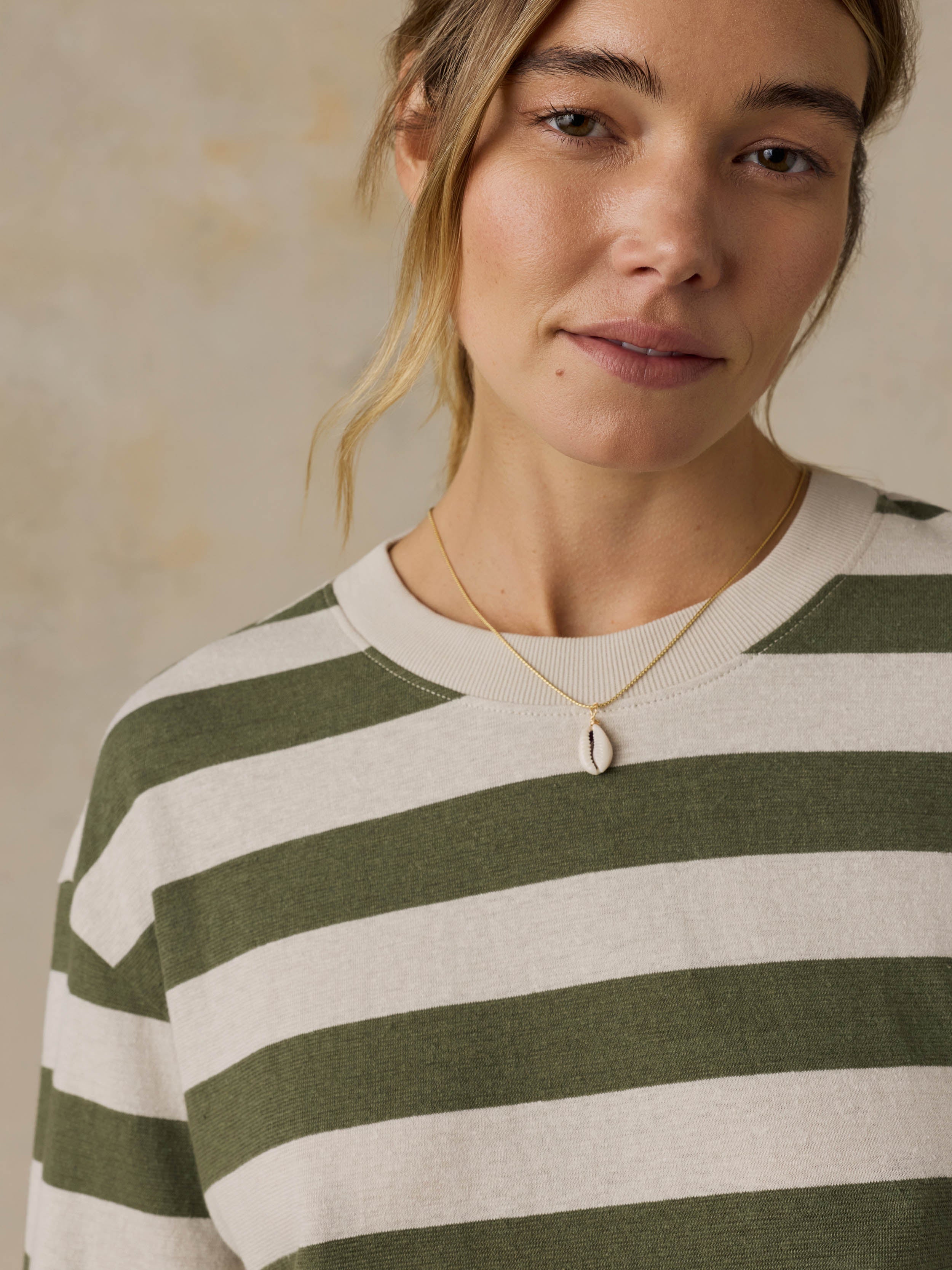 Woman wearing a green and white striped shirt against a beige background