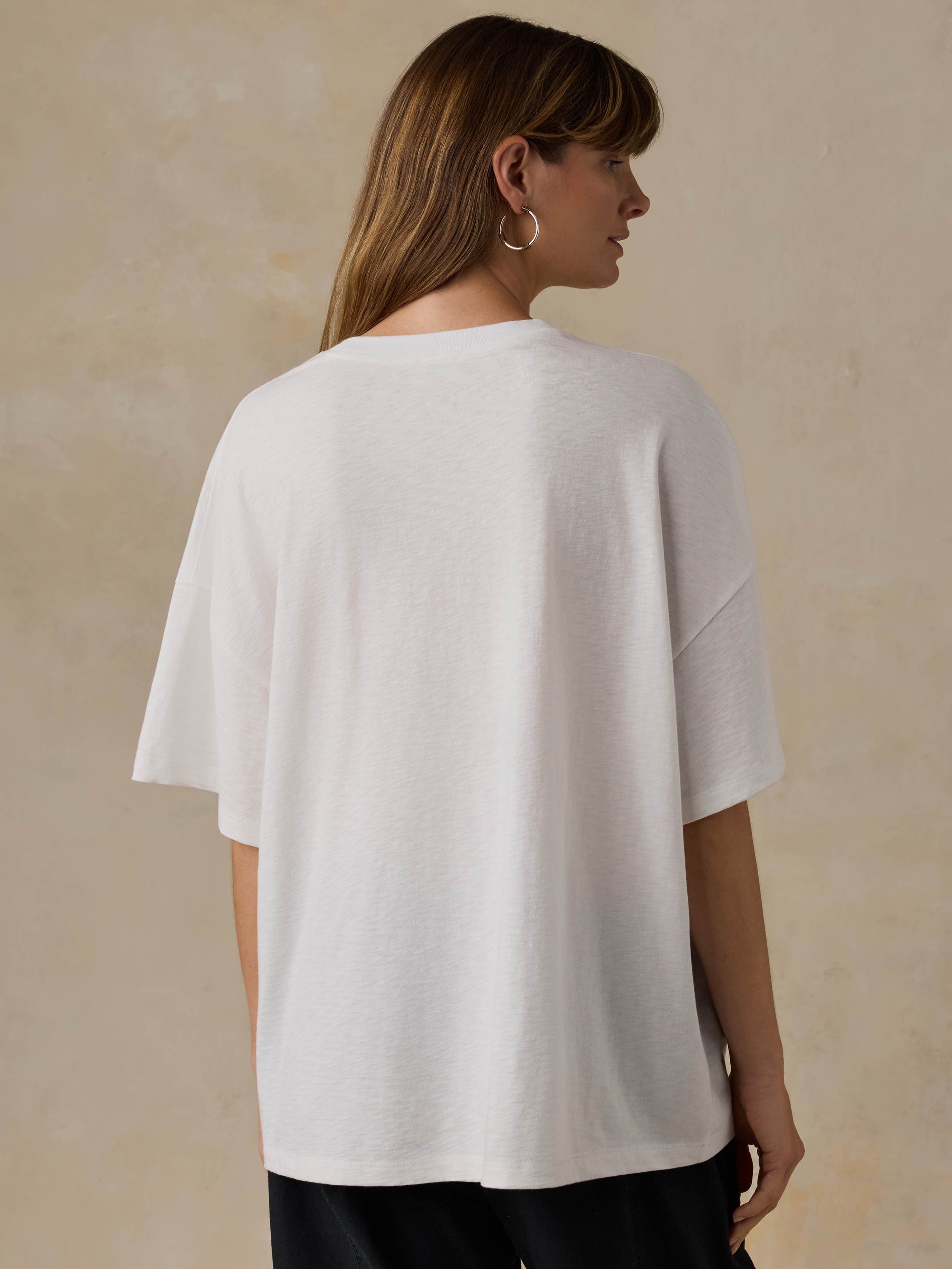 Woman wearing a white t-shirt and black pants against a beige background