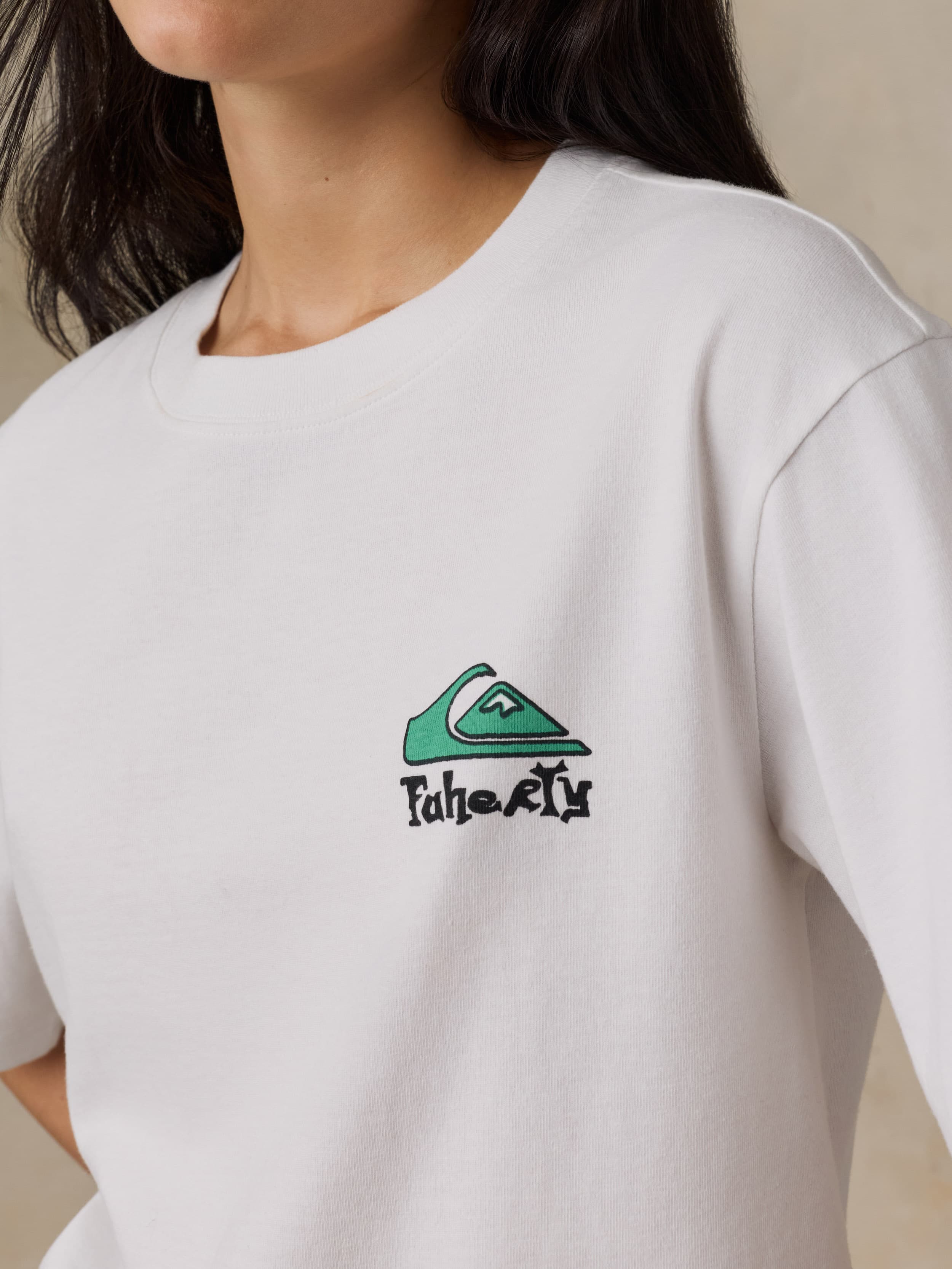 White t-shirt with a green and black logo on a neutral background