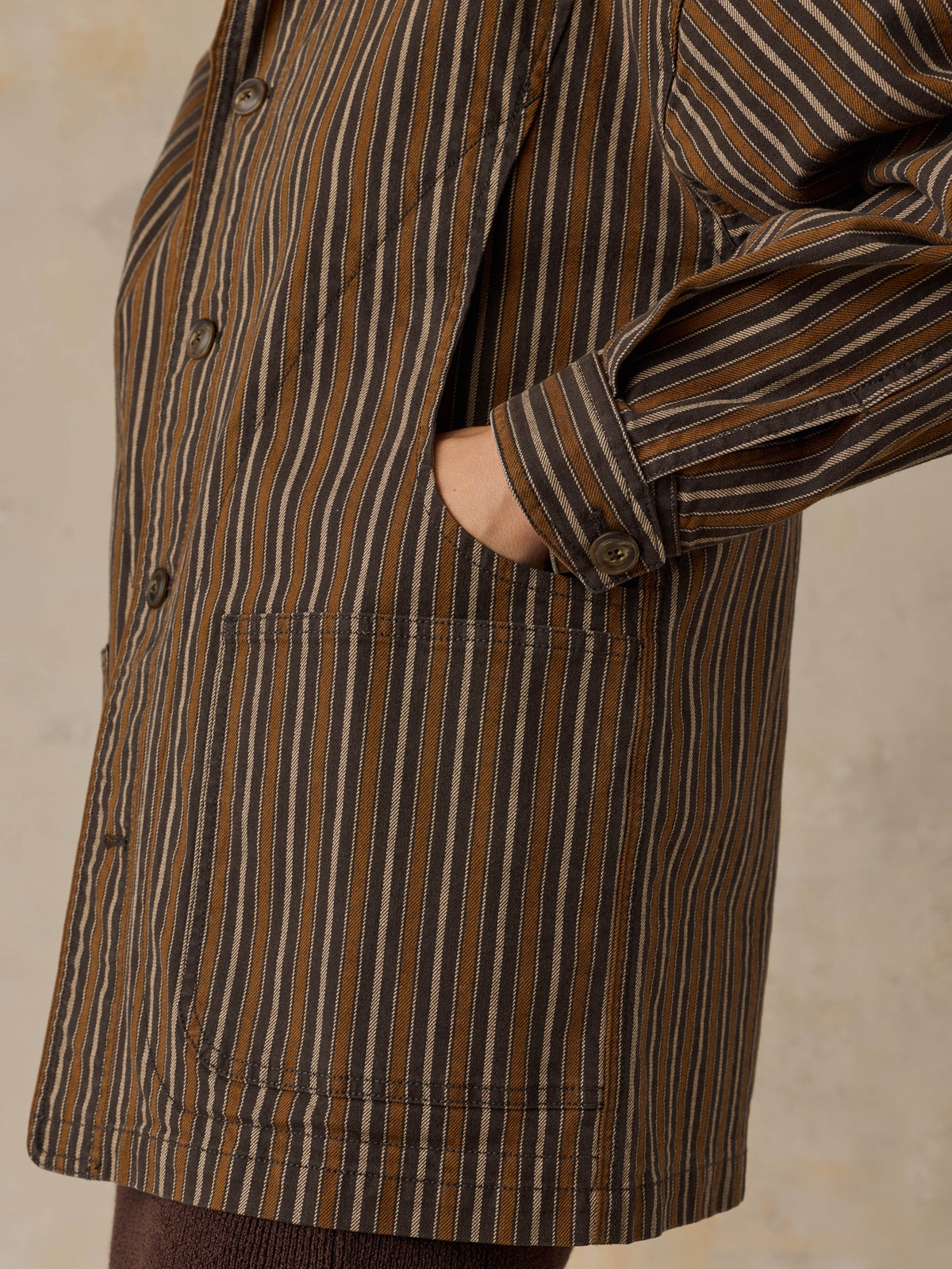 Woman wearing a brown striped chore jacket against a beige background, image 3 of 6