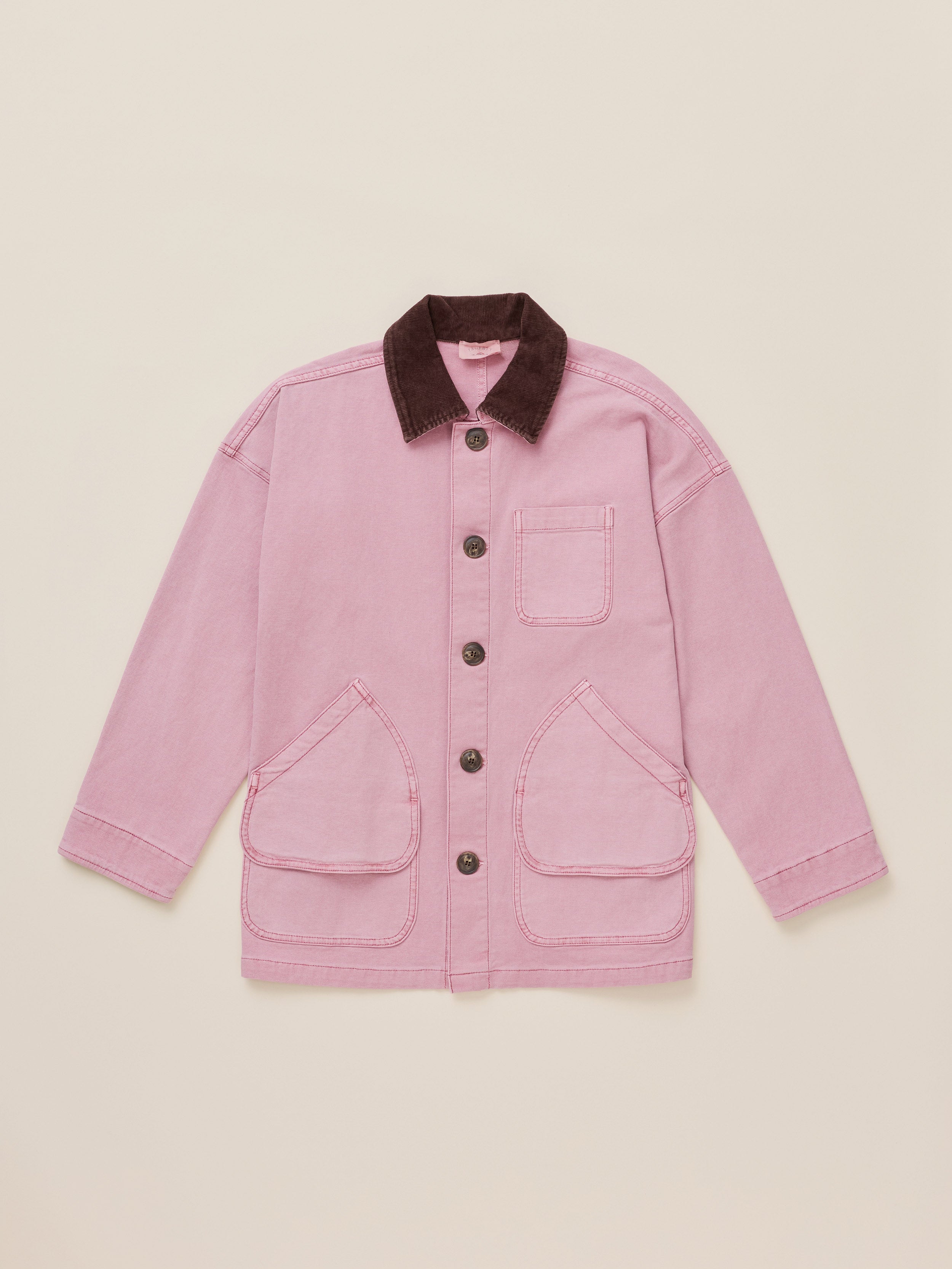 A pink canvas utility jacket with a dark brown corduroy collar, featuring a button-up front, a chest pocket, and two large front flap pockets, laid flat on a light beige background.