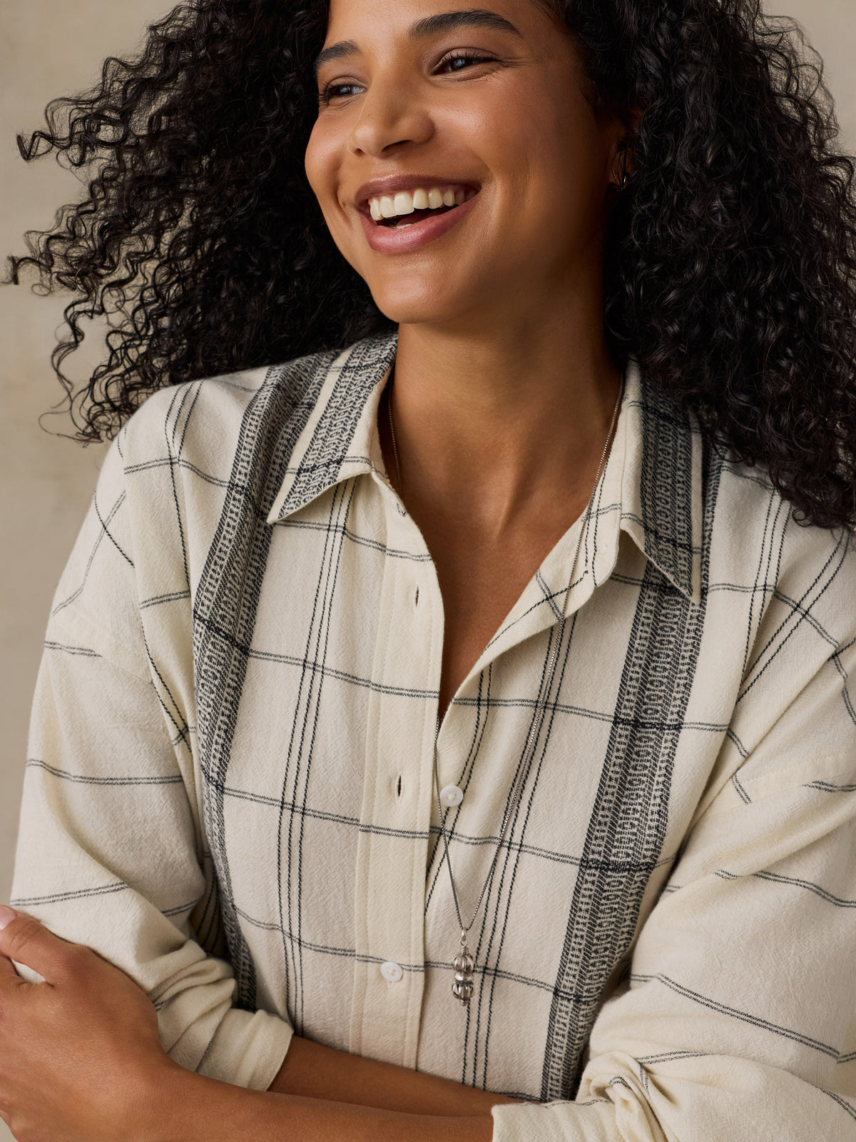 Woman wearing a white and black plaid shirt against a beige background, image 4 of 6