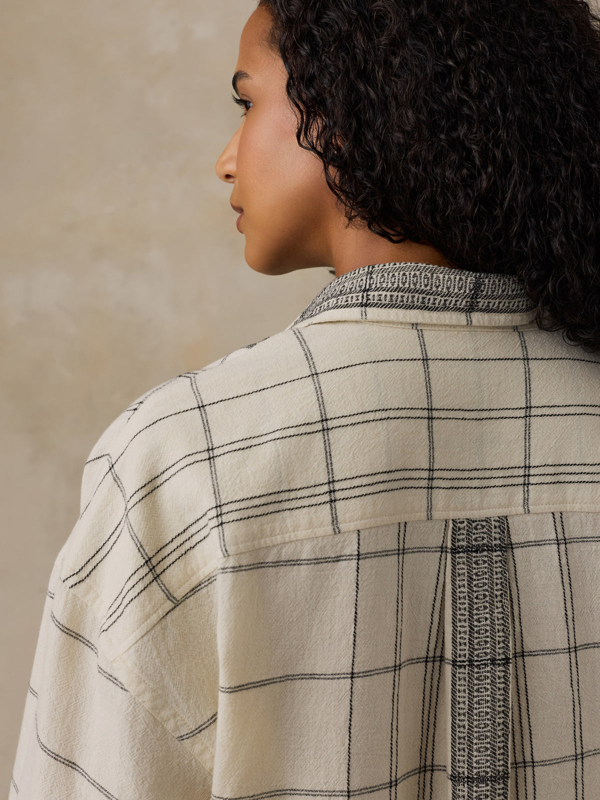 Woman wearing a white and black plaid shirt against a beige background, image 5 of 6