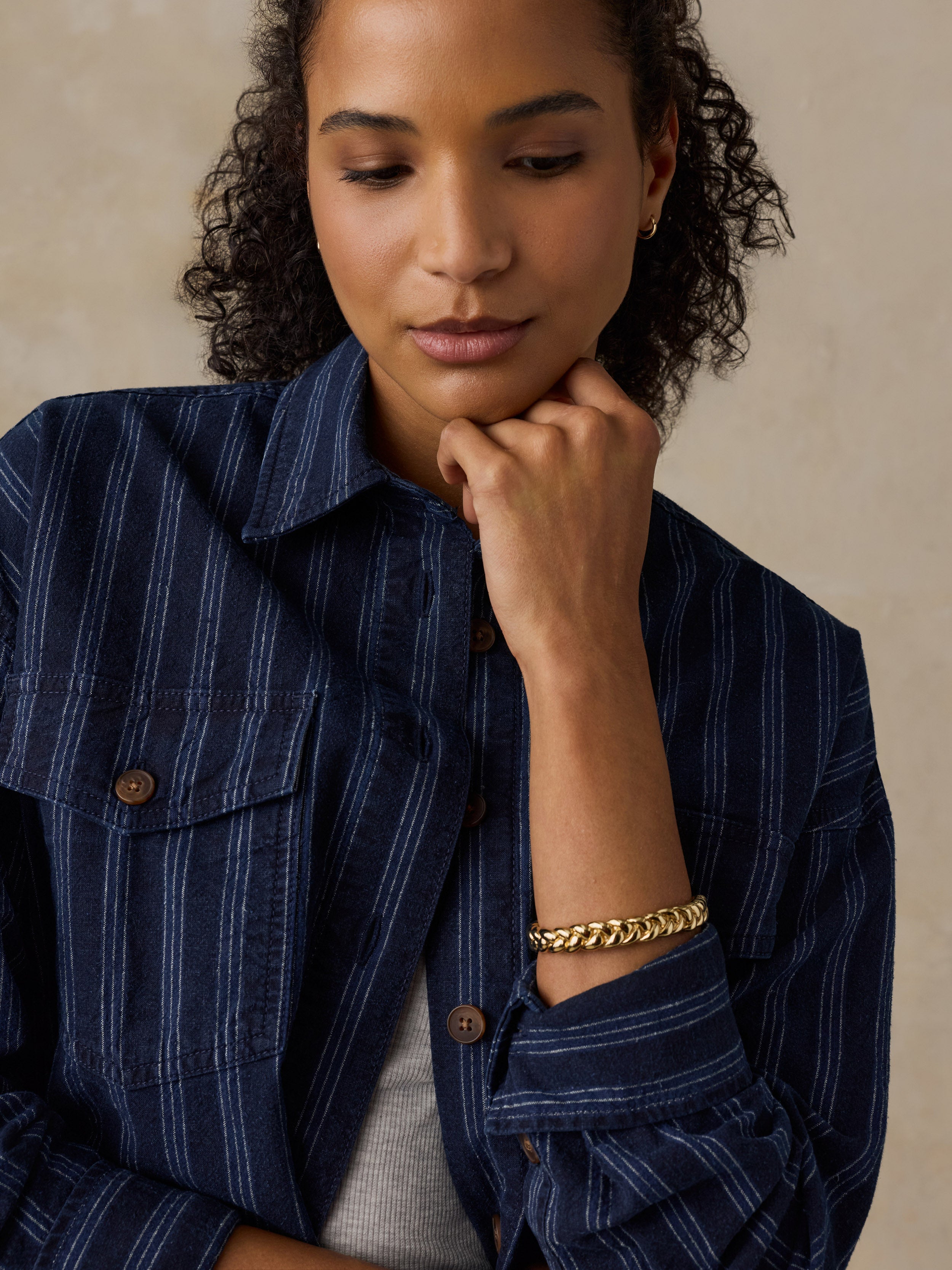 Woman wearing a navy striped overshirt against a beige background