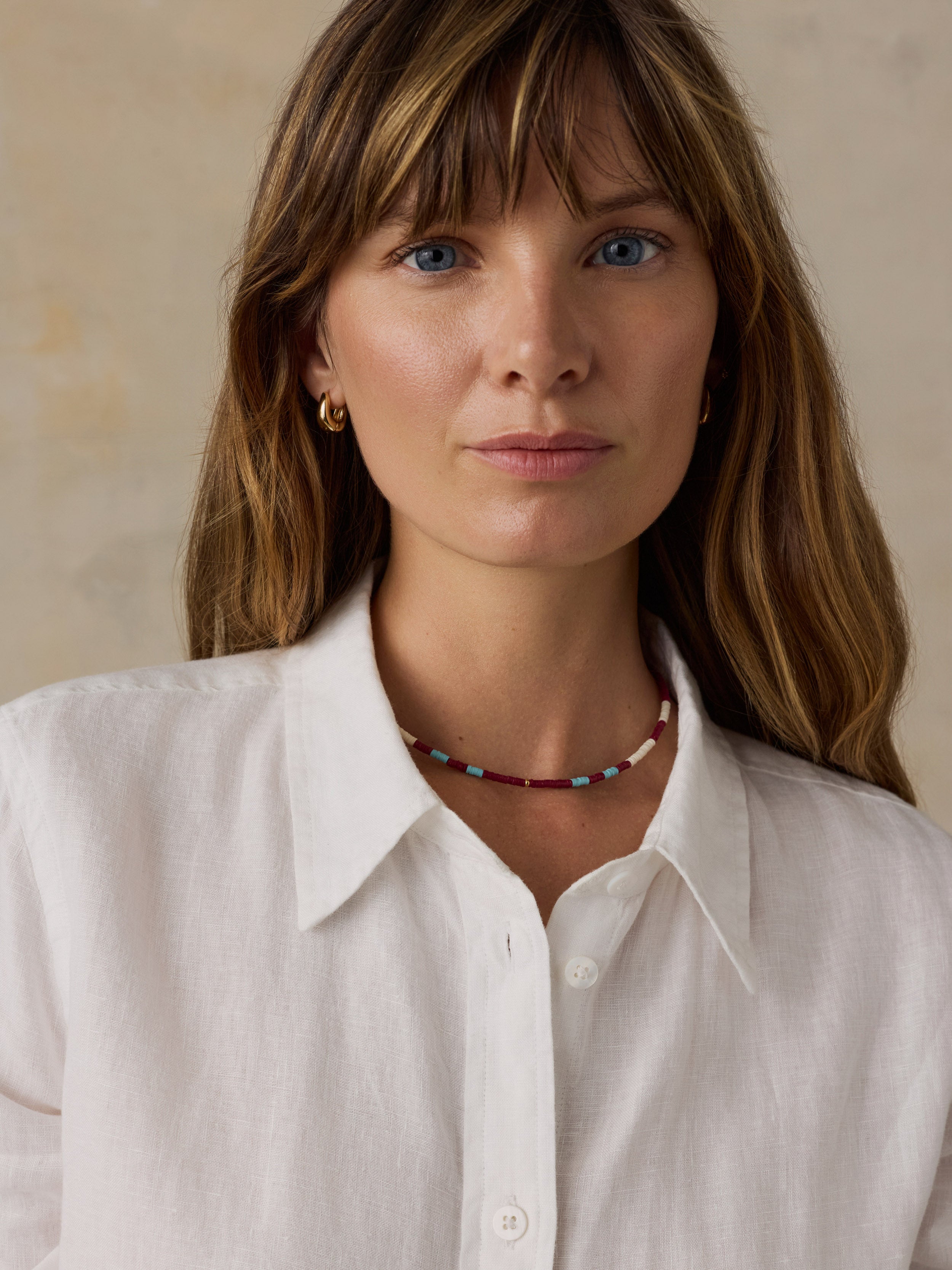 Woman wearing a white linen shirt against a beige background