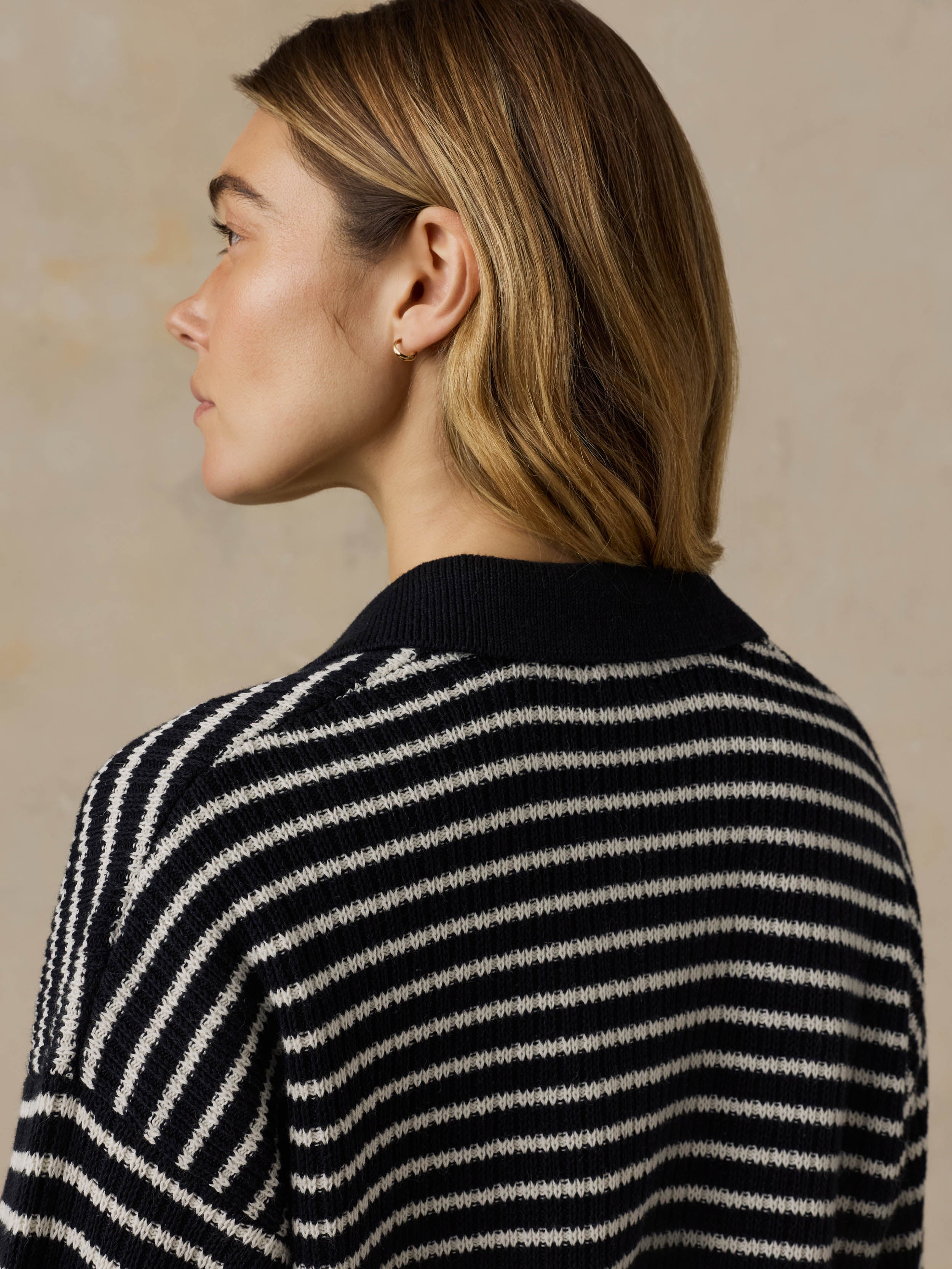 Woman wearing a blue and white striped sweater against a beige background