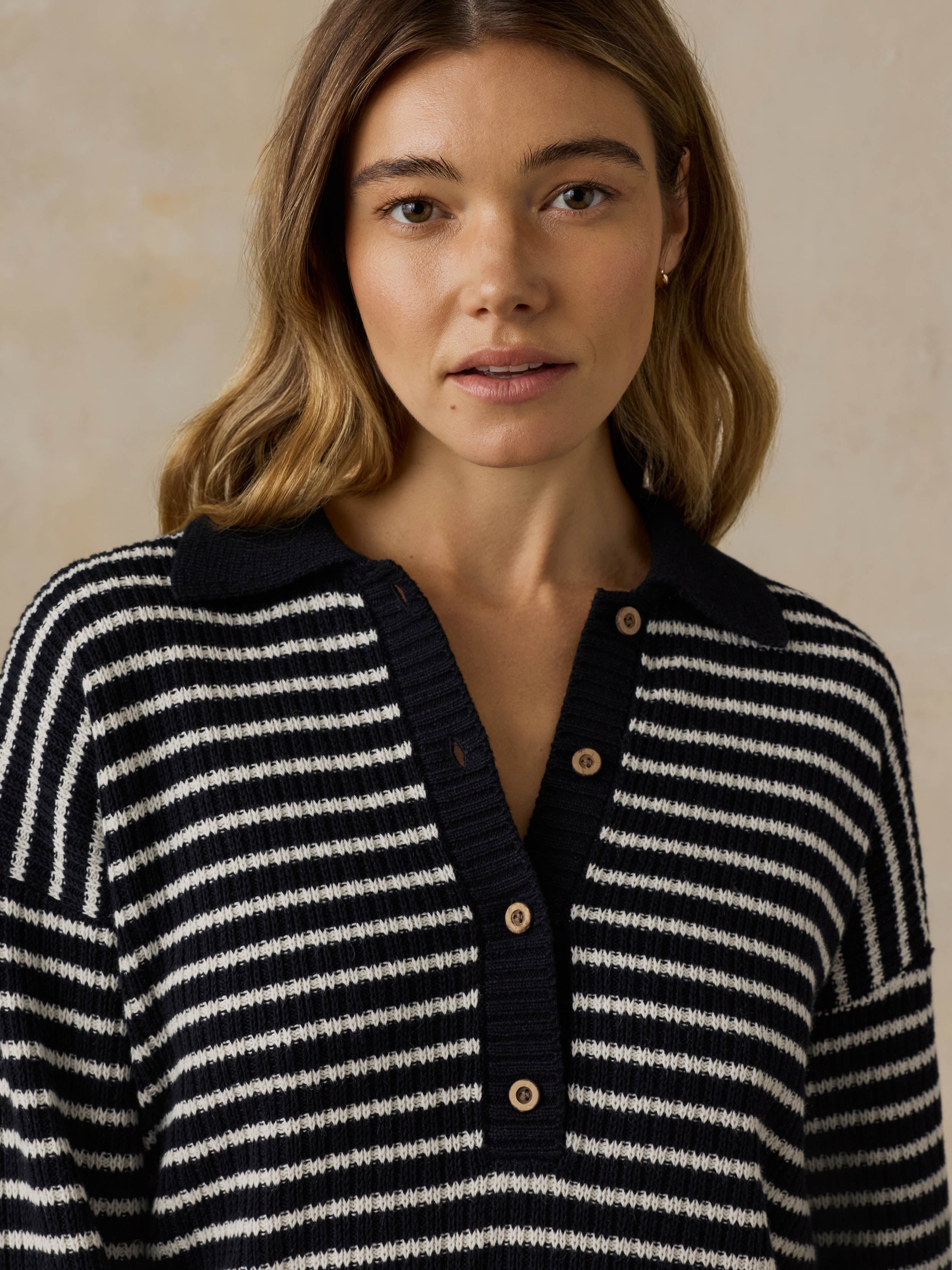 Woman wearing a blue and white striped sweater against a beige background