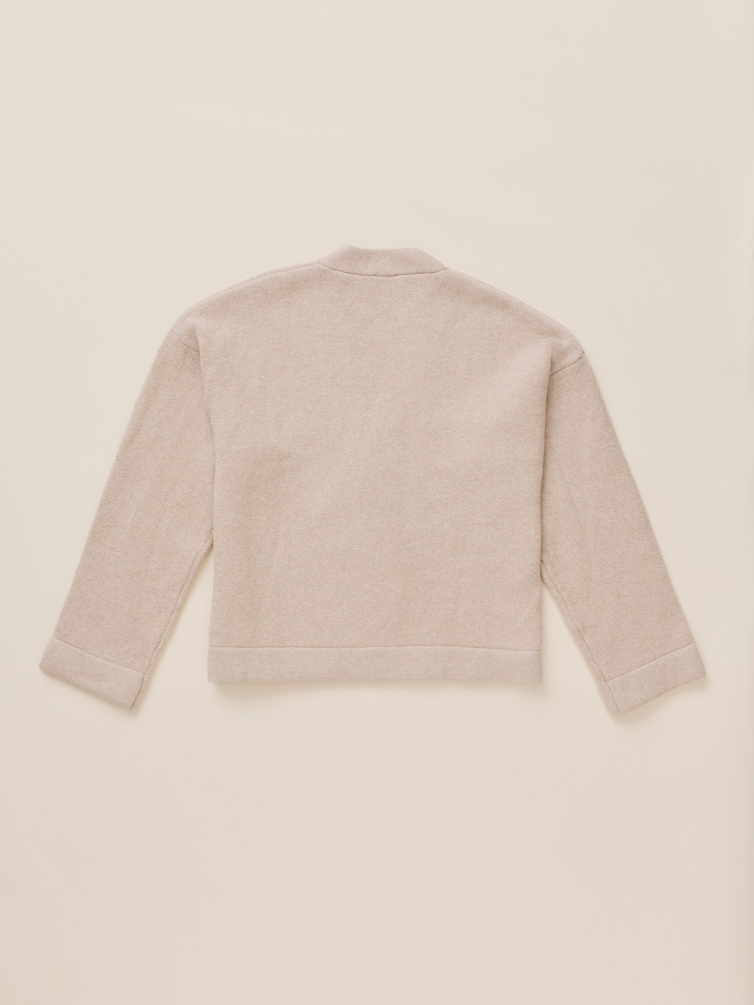 A light beige knit cardigan shown from the back, laid flat on a matching light beige background.