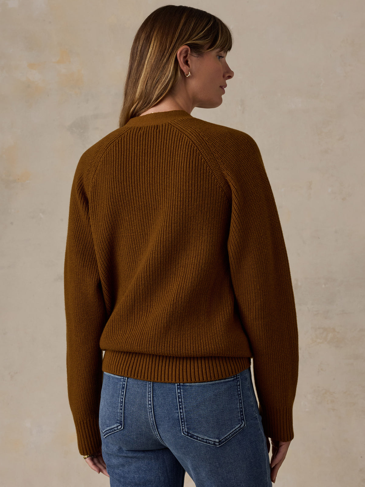A woman wearing a ribbed knit sweater in a warm camel brown color, paired with blue jeans, image 3 of 5