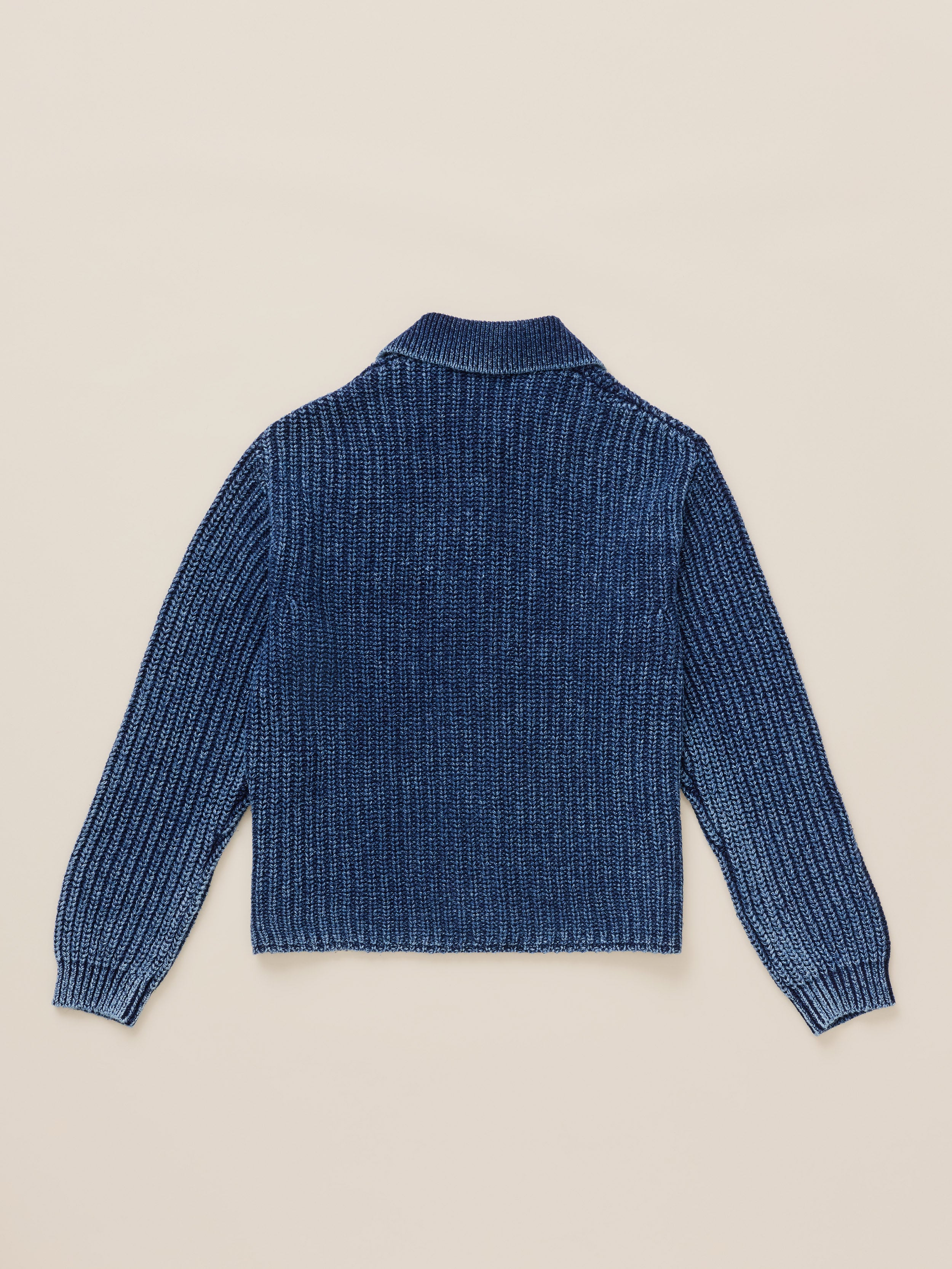 Blue cardigan viewed from the back against a warm beige studio background