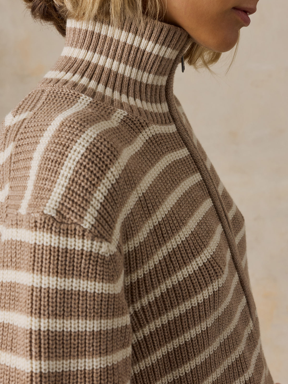 A woman wearing a beige and brown striped quarter-zip pullover sweater, image 3 of 5