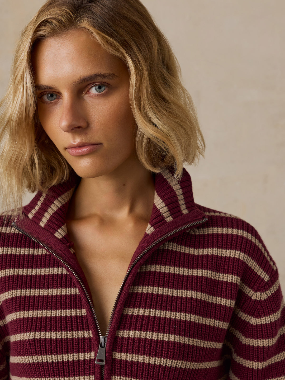 A woman wearing a burgundy and beige striped quarter-zip knit sweater, image 2 of 5