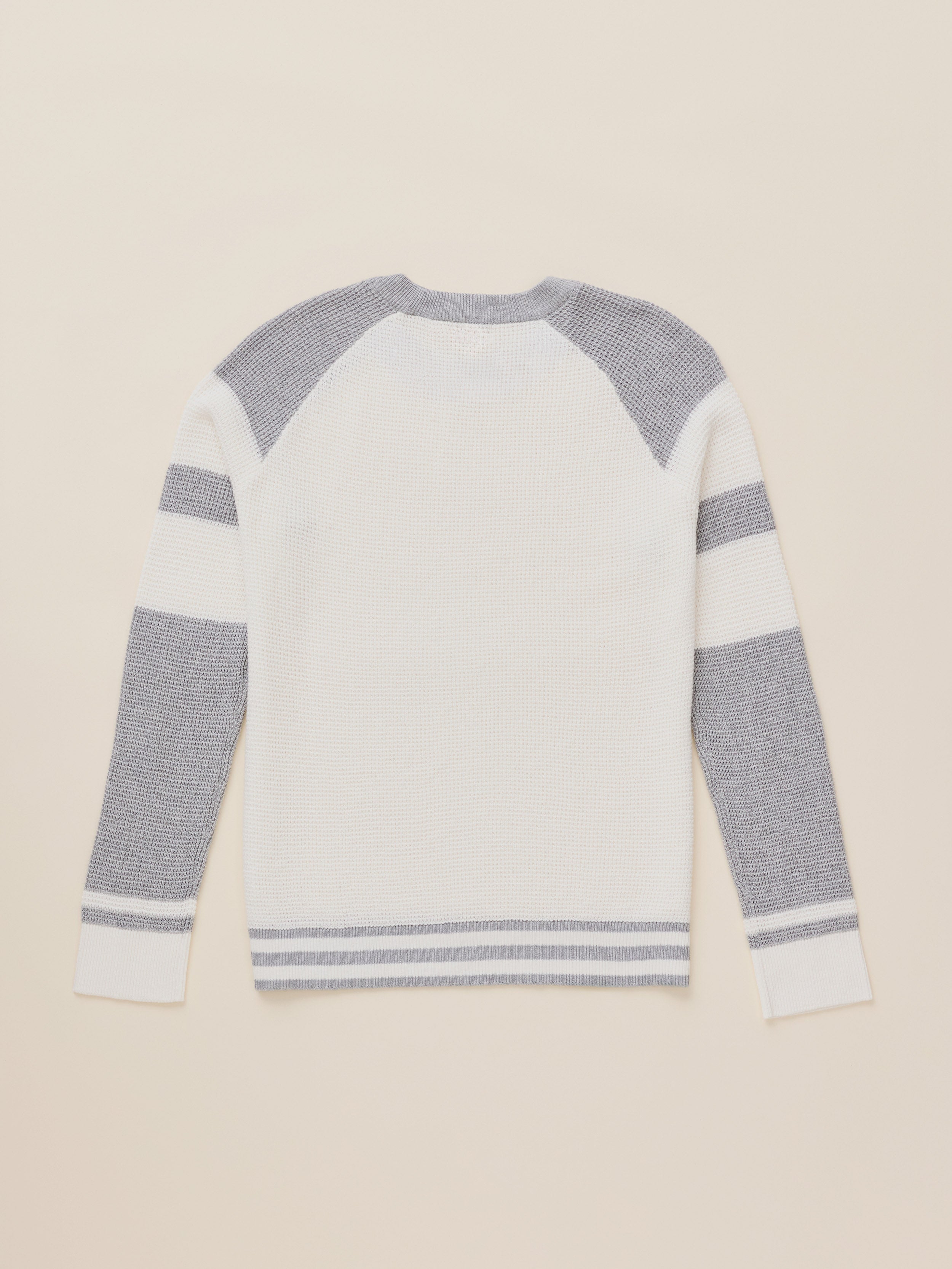 A white and gray striped knit sweater shown from the back, laid flat on a light beige background.