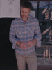 Video of a man wearing a blue plaid shirt and beige pants