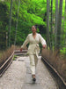 Video of a woman wearing a cream cardigan and white pants walking in a bamboo forest
