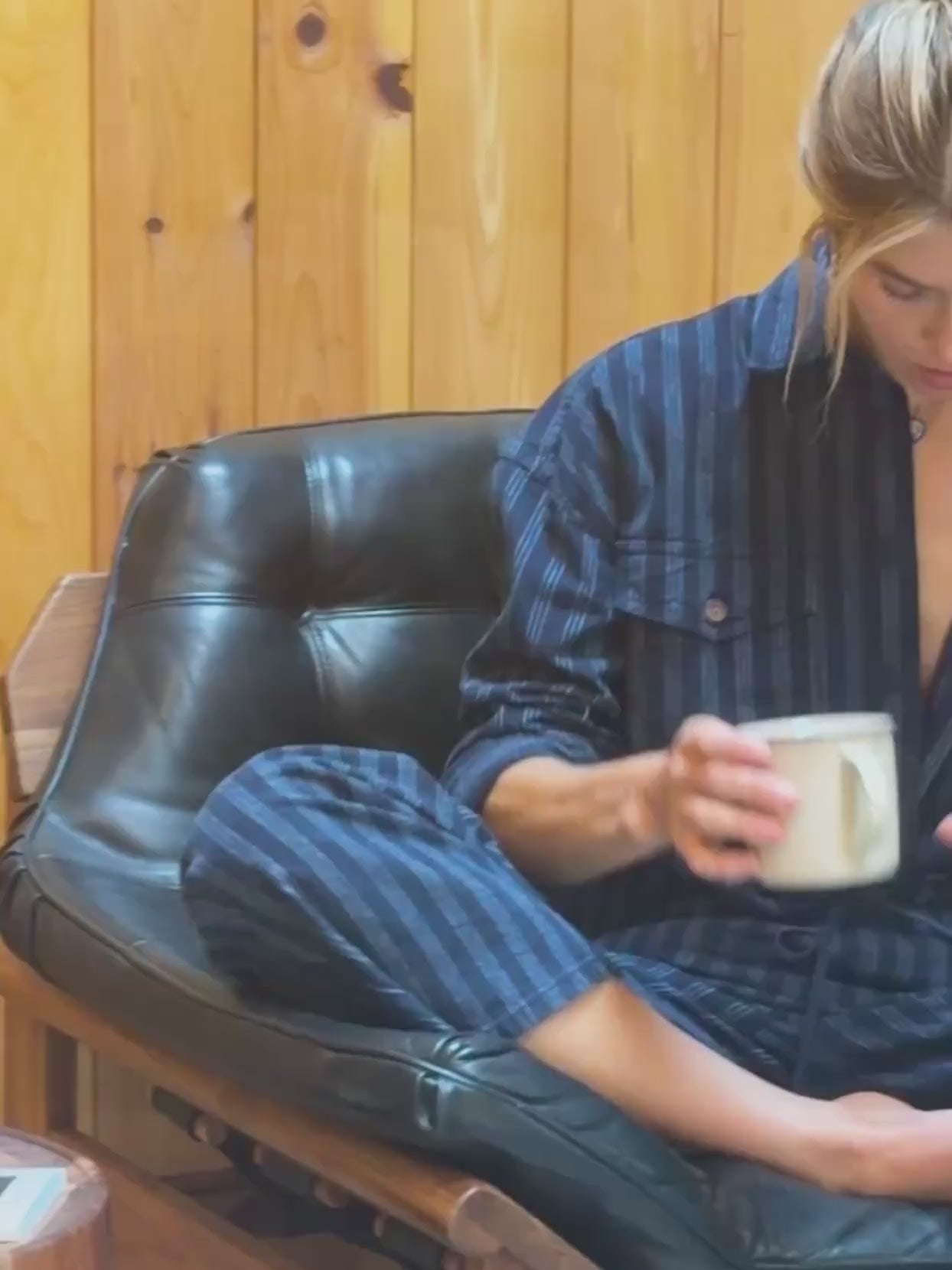 Video of a woman wearing a blue striped set sitting in a leather chair