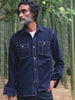 Man wearing an indigo jacket standing outside in a bamboo forest
