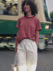 Video of a woman wearing a red striped tee and white pull on pants standing in front of a train