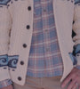 Video of a man wearing a white wave print cardigan over a blue plaid shirt