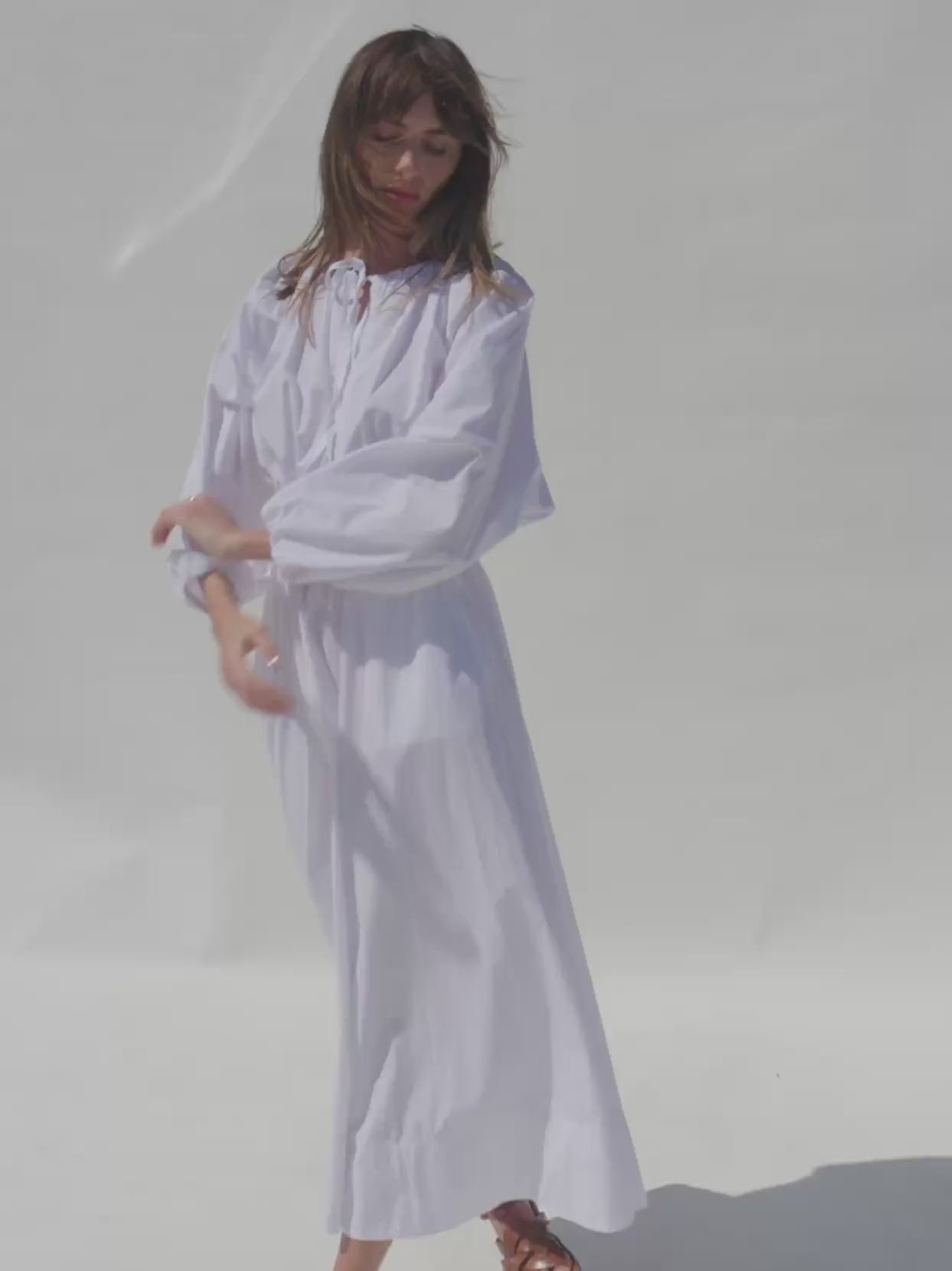 Video of a woman wearing a white poplin top and matching skirt against a white background