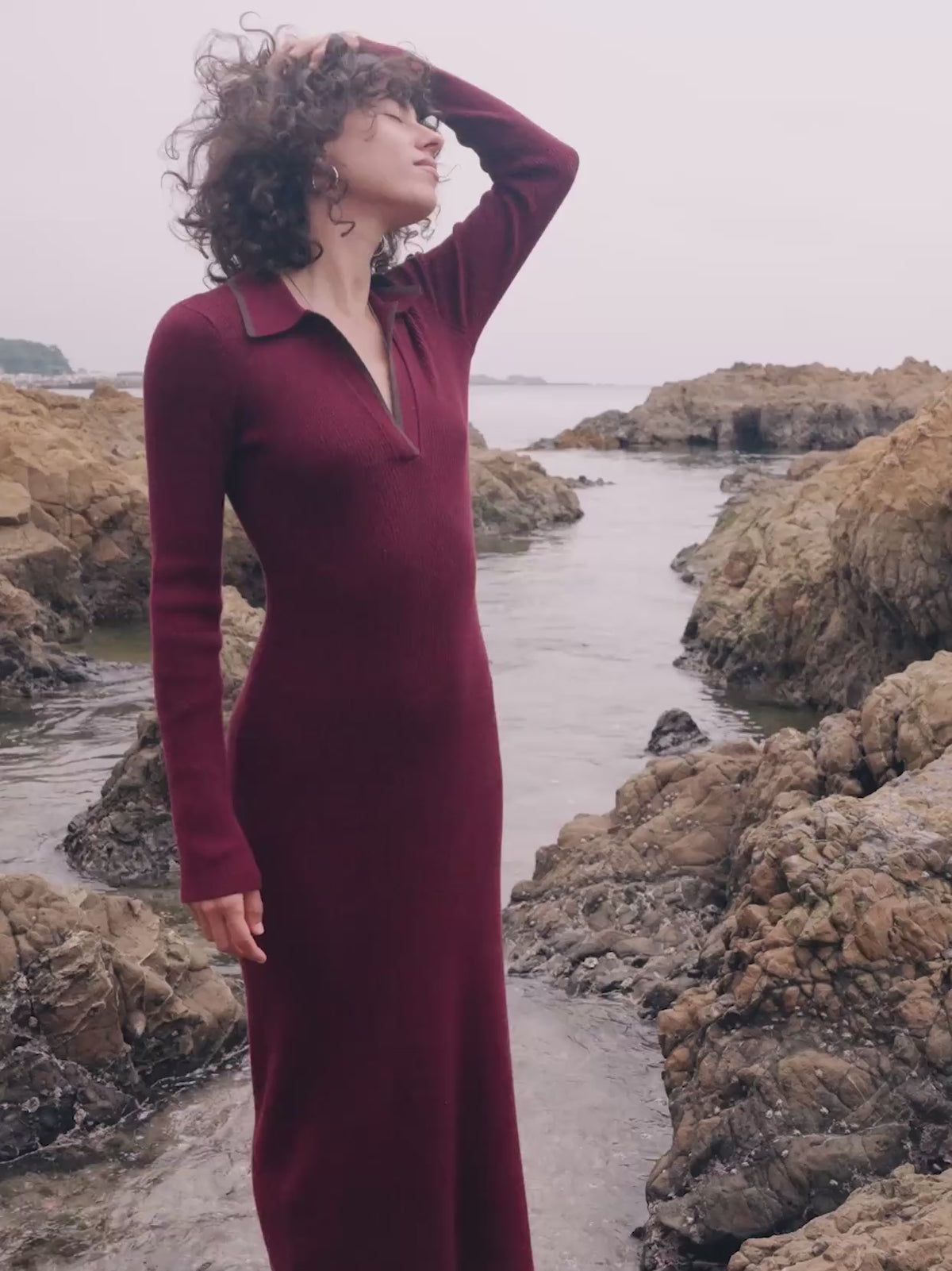 Video of a woman wearing a red maxi dress standing in tidepools